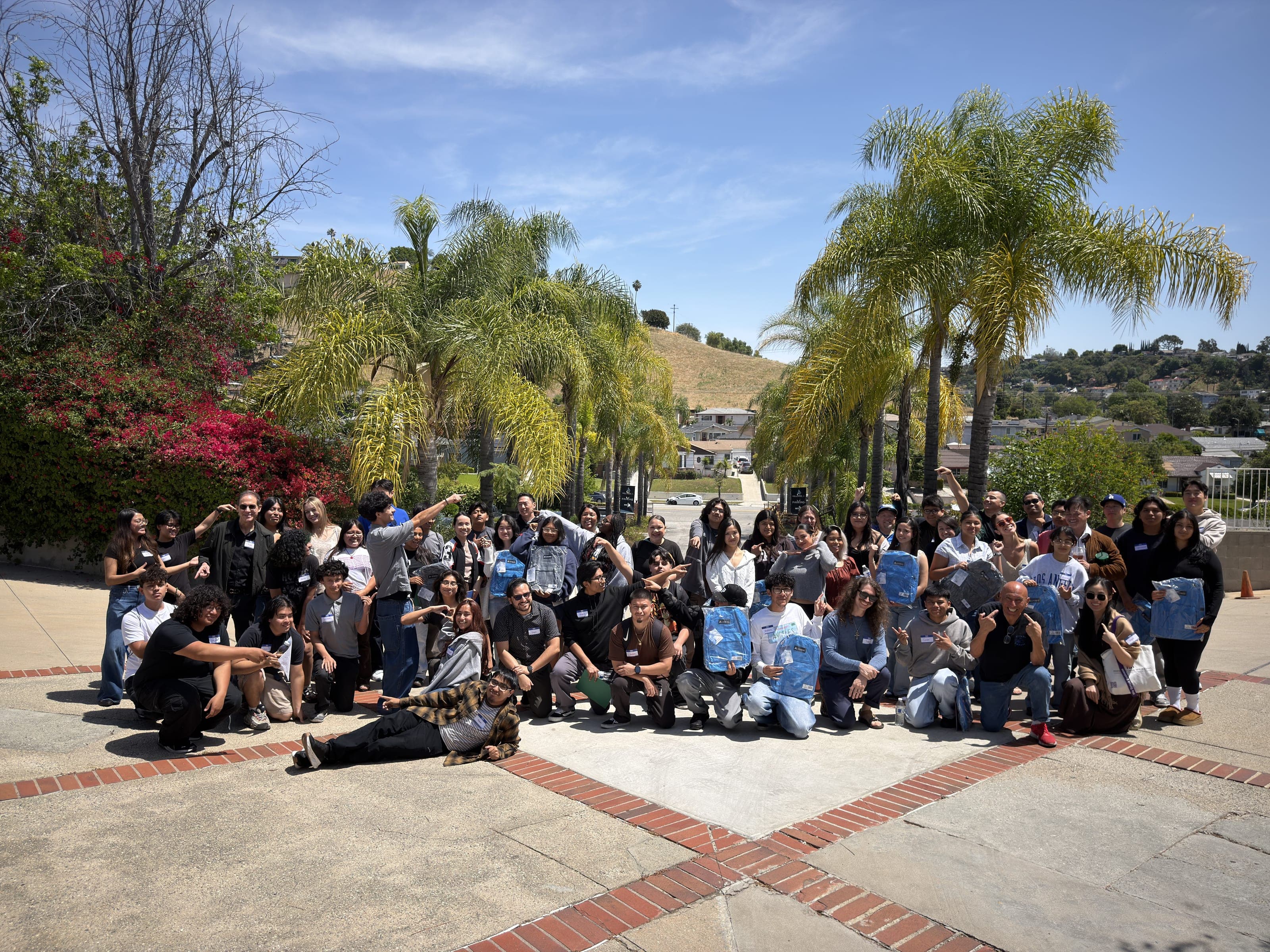 A large group of Mentor For Change mentors, mentees, and staff posing together outdoors