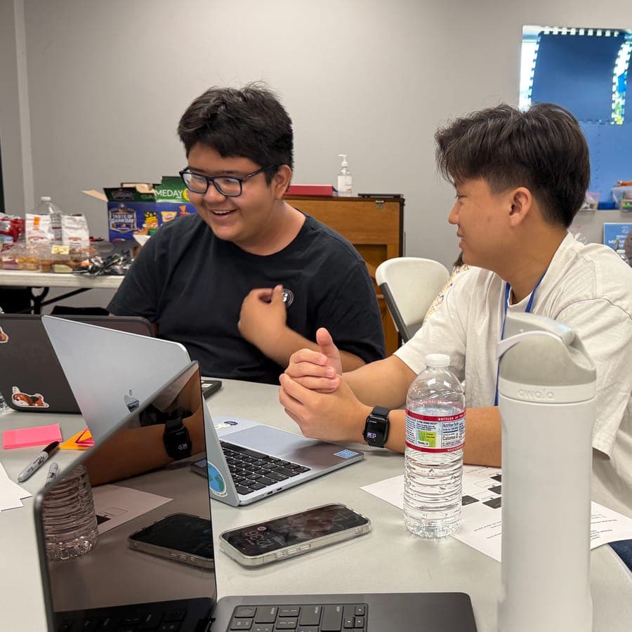 A mentor and mentee laughing together at a workshop table
