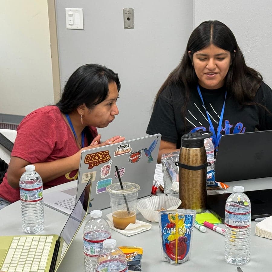 A mentor and a young person working together over a laptop at a workshop